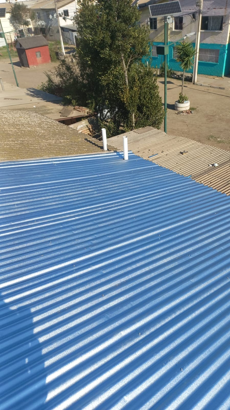 Techumbre de zinc color azul terminada sobre vivienda, sector residencial